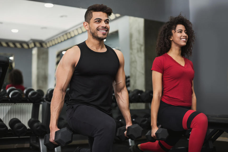 Couple doing lunges with dumbbells in gym