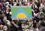 A man holds a sign directed at President Jair Bolsonaro that reads in Portuguese "Get out Bolsonaro. Another Brazil is possible" prior the reading of one of two manifestos defending the nation's democratic institutions and electronic voting system outside the Faculty of Law at Sao Paulo University in Sao Paulo, Brazil, Thursday, Aug. 11, 2022. The two documents are inspired by the original “Letter to the Brazilians” from 1977 denouncing the brutal military dictatorship and calling for a prompt return of the rule of law. (AP Photo/Andre Penner)