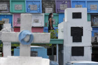 A man wearing a face mask to prevent the spread of the coronavirus walks past tombs at the North Cemetery on Wednesday, Oct. 28, 2020, in Manila, Philippines. The government has ordered all private and public cemeteries, memorial parks, and columbariums to be closed from Oct. 29 to Nov. 4, 2020, to prevent people from gathering during the observance of the traditionally crowded All Saints Day and to help curb the spread of the coronavirus. (AP Photo/Aaron Favila)