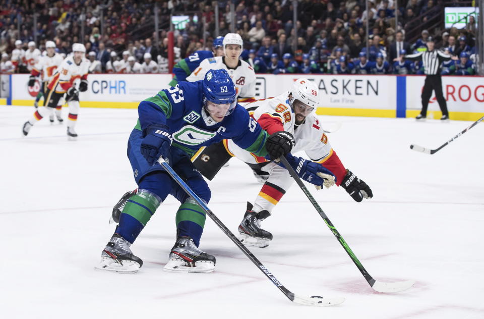 Vancouver Canucks' Bo Horvat (53) skates with the puck past Calgary Flames' Oliver Kylington (58), of Sweden, during the second period of an NHL hockey game Saturday, Feb. 8, 2020, in Vancouver, British Columbia. (Darryl Dyck/The Canadian Press via AP)