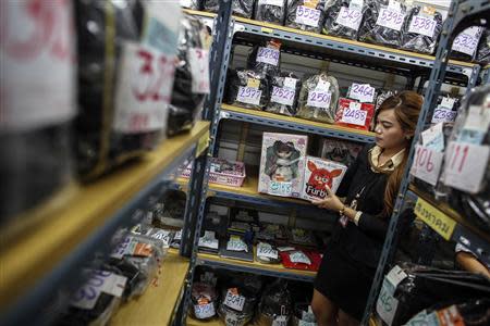 A pawn shop worker poses for a photograph as she holds a Blythe doll and a Furby doll as items from customers at Easy Money pawn shop in Bangkok, August 27, 2013. REUTERS/Athit Perawongmetha