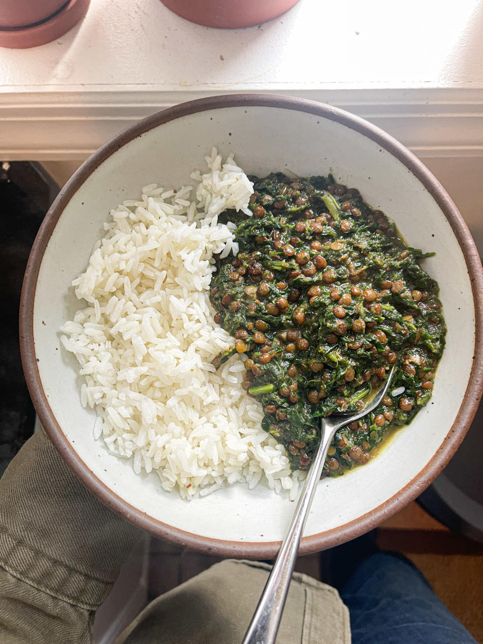 Bowl of lentils and spinach in curry next to rice