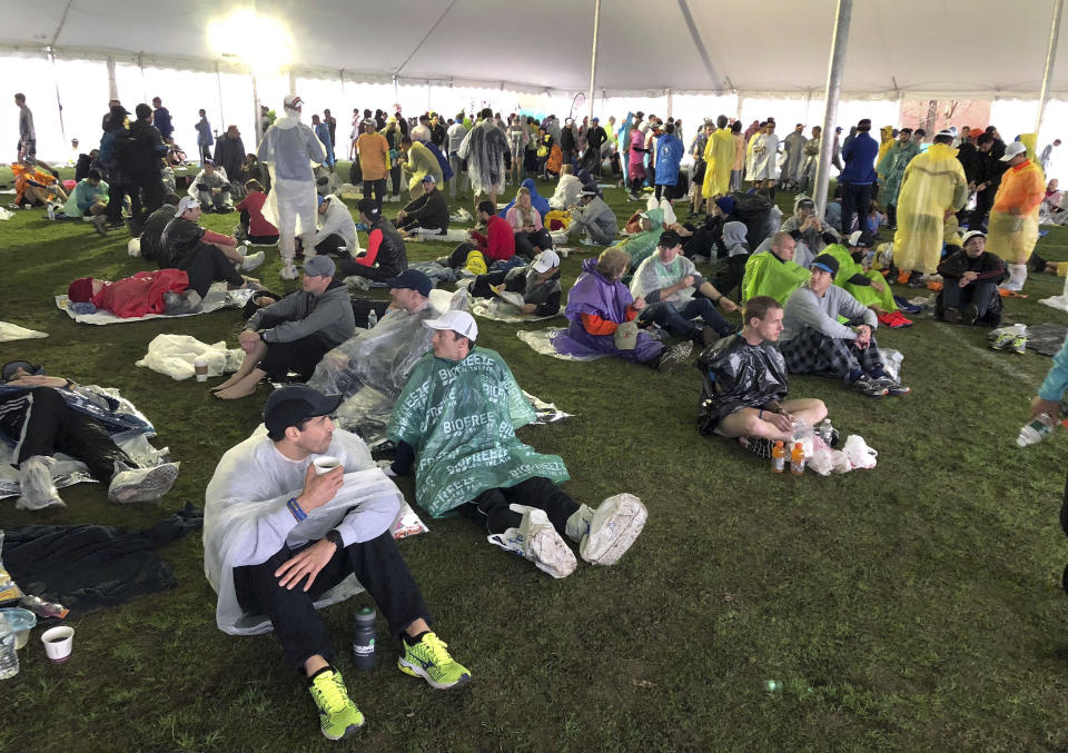 Runners wait under a tent while it rains before the start of the 123rd Boston Marathon on Monday, April 15, 2019, in Hopkinton, Mass. (AP Photo/Jennifer McDermott)