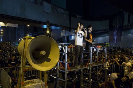 Student leaders of the Occupy Central civil disobedience movement, Alex Chow (L), secretary-general of the Hong Kong Federation of Students, and Joshua Wong, who heads the group Scholarism that represents secondary school pupils, deliver a speech as protesters block the main street to the financial Central district, outside the government headquarters building in Hong Kong October 11, 2014. REUTERS/Tyrone Siu