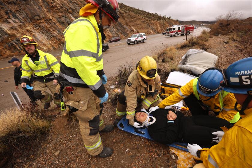 NIPTON, CA - MARCH 16, 2024 - - Engineer/paramedic Jeff Garcia, from left, Captain Dan Tellez, standing, paramedic Brian Bement, EMT Ray Barron and paramedic Eric Butikofer, right, with Los Angeles County Fire Dept. Station 53 from Baker, stabilize a car accident victim who was thrown from her vehicle along I-15 at Mountain Pass in Nipton, California, on March 16, 2024. Station 53, based in Baker, California, is the only emergency medical services along the I-15, one of the busiest freeway corridors in the country. Sometimes it takes the crew an hour or more to reach the scene of an accident. (Genaro Molina/Los Angeles Times)