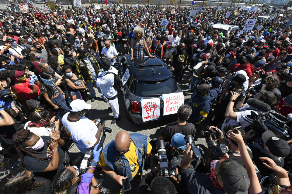 Thousands of people surround activist Angela Davis as she speaks to protesters during the West Coast Port Shutdown held at the SSA Terminals in Oakland, Calif., on Friday, June 19, 2020. Cranes and berths came to a standstill as longshoremen in ports throughout California stopped work Friday, joining thousands of Californians who marched, rallied and drove in car caravans to commemorate Juneteenth and demand racial equality. (Jose Carlos Fajardo/Bay Area News Group via AP)