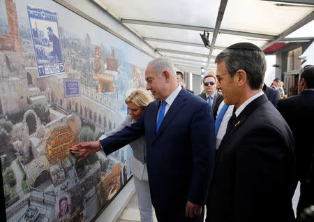 Israeli Prime Minister Benjamin Netanyahu and his wife Sara touch a mural alongside Agustin Zbar, President of the Argentine Israeli Mutual Association (AMIA) Jewish community center, as they visit the AMIA building, which was bombed in 1994, in Buenos Aires, Argentina September 11, 2017. Embassy of Israel in Buenos Aires/Handout via REUTERS