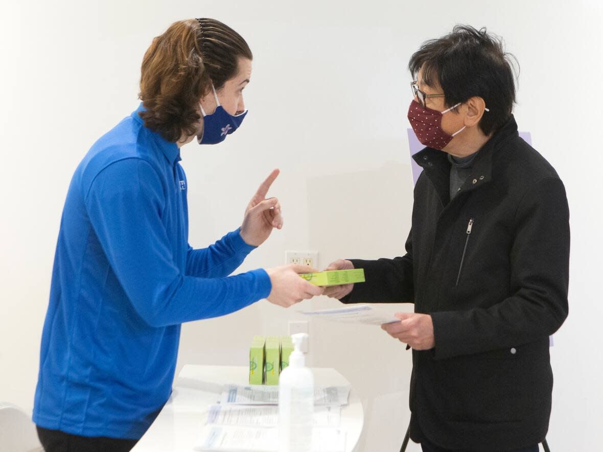 A man receives a free COVID-19 rapid antigen test kit at a pop-up site in Toronto this month. Here's a guide on how and when to use it. (Chris Young/Canadian Press - image credit)