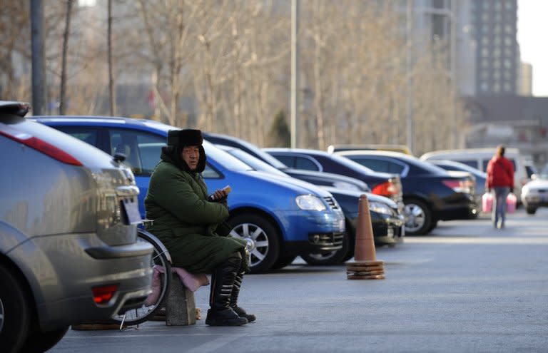 A parking attendant sits on duty beside cars in a car park downtown Beijing on January 17, 2011. A two-year-old Chinese girl was in critical condition Thursday after being thrown to the ground by a man in a row with her mother over parking, a hospital and state media said