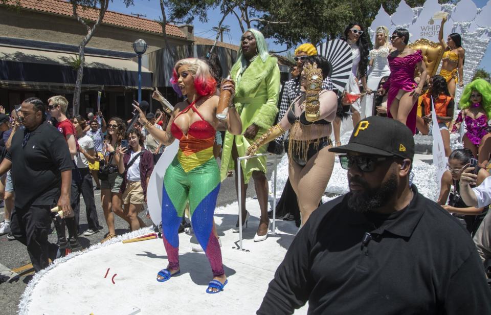 Cardi B., in a rainbow jumpsuit, on a float