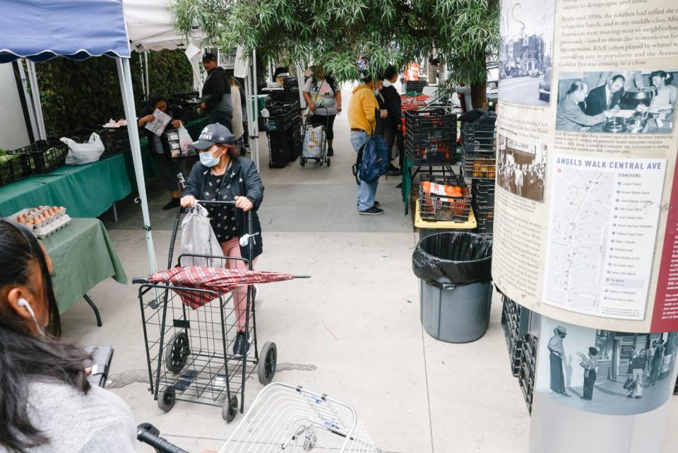 People on a sidewalk filled with stalls.