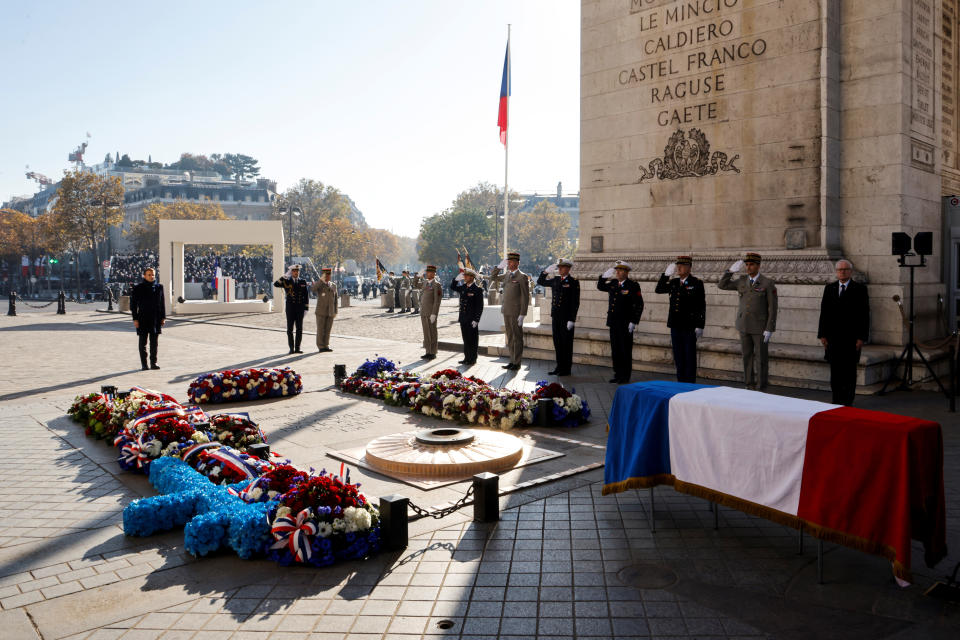 French President Emmanuel Macron stands at attention at the Tomb of the Unknown Soldier under the Arc de Triomphe, by the coffin of Hubert Germain, during ceremonies marking the 103rd anniversary of Armistice Day, Thursday, Nov. 11, 2021 in Paris. Wreath-laying ceremonies will take place across the country, while in Paris there will be a tribute to the last remaining participants in the liberation of France from the Nazis, Hubert Germain, who recently died aged 101. (Ludovic Marin, Pool via AP)