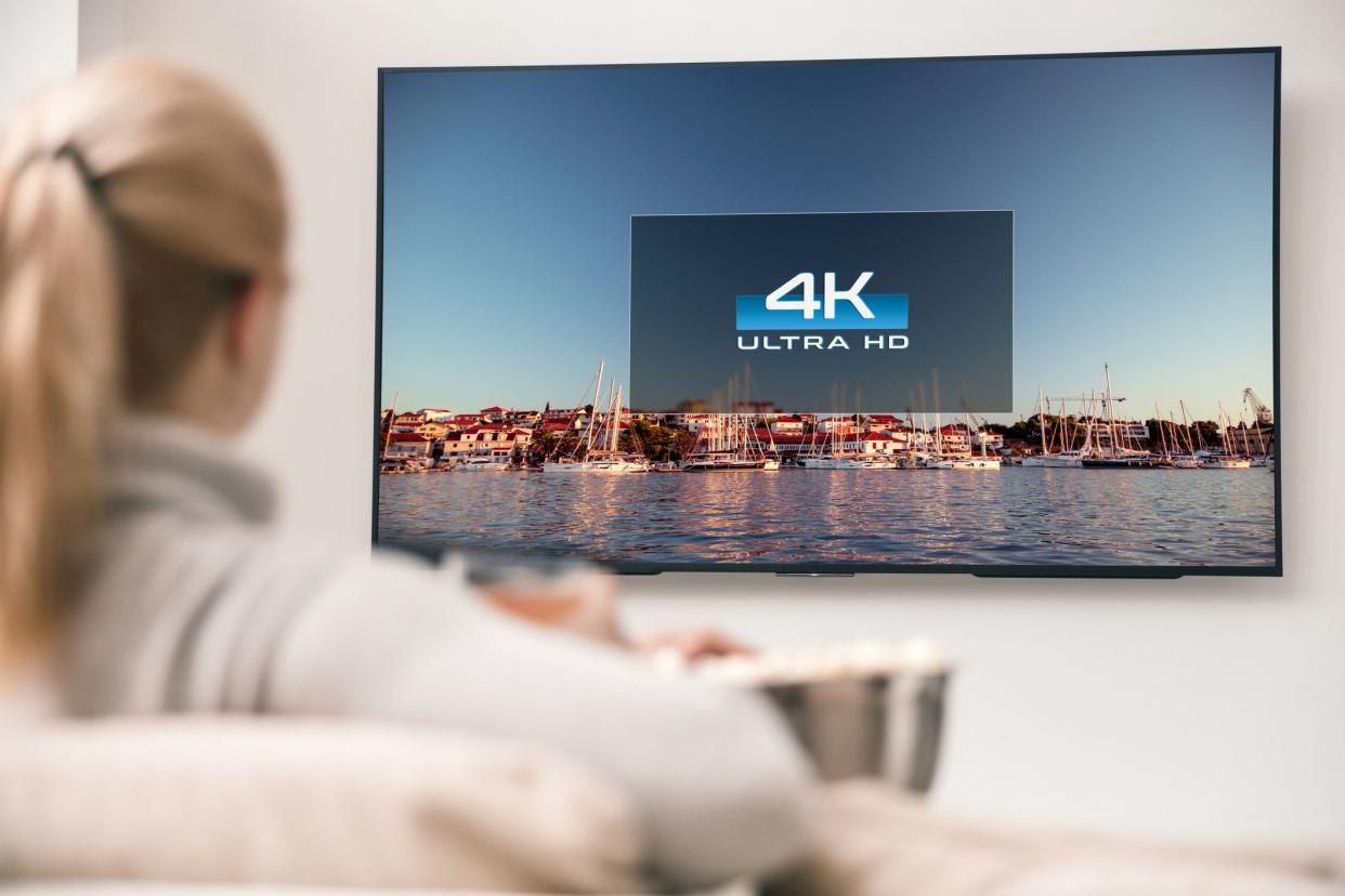 back of woman's head looking at 4k tv on wall