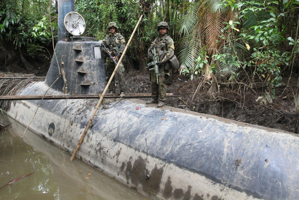Members of the Colombian Navy stand guard on top of a seized submarine built by drug smugglers in a makeshift shipyard in Timbiqui, department of Cauca February 14, 2011. Colombian authorities said the submersible craft was to be used to transport 8 tons of cocaine illegally into Mexico. REUTERS/Jaime Saldarriaga