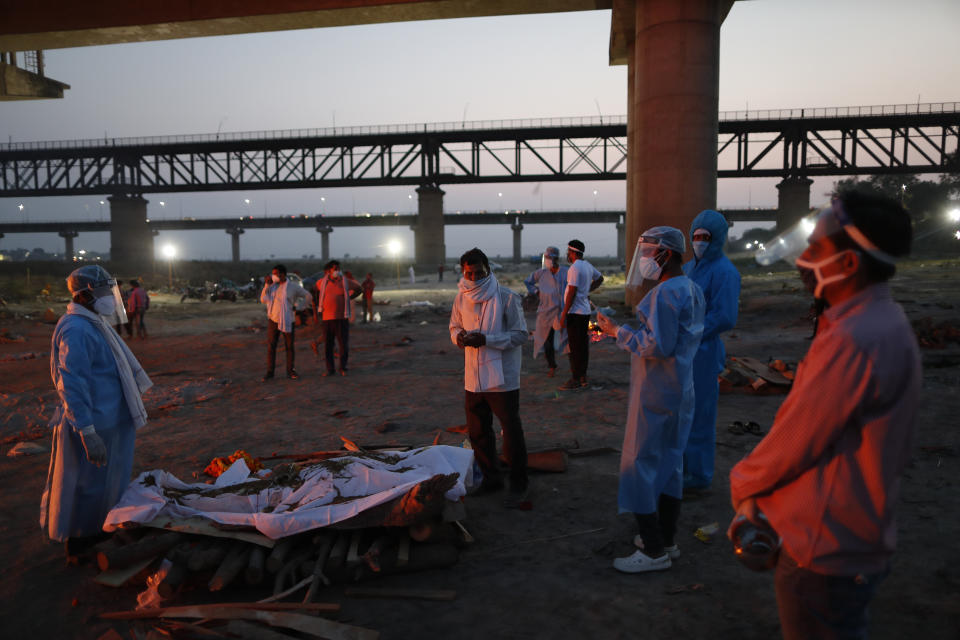 Relatives stand near the funeral pyre of their loved one who died due to COVID-19 at a cremation ground in Prayagraj, India, Saturday, May 8, 2021. (AP Photo/Rajesh Kumar Singh)