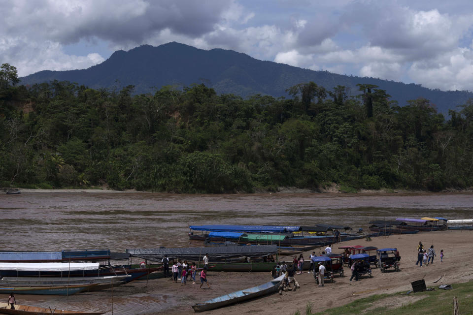 Residents travel over Huallaga's river in Chazuta community with the background of Cordillera Azul National Park in Peru's Amazon, Sunday, Oct. 2, 2022. Analysis by independent experts and reporting by The Associated Press raise doubts about whether a program to sell carbon credits is delivering on its promise to stop deforestation in the park and balance out carbon emissions by the companies buying the credits. (AP Photo/Martin Mejia)