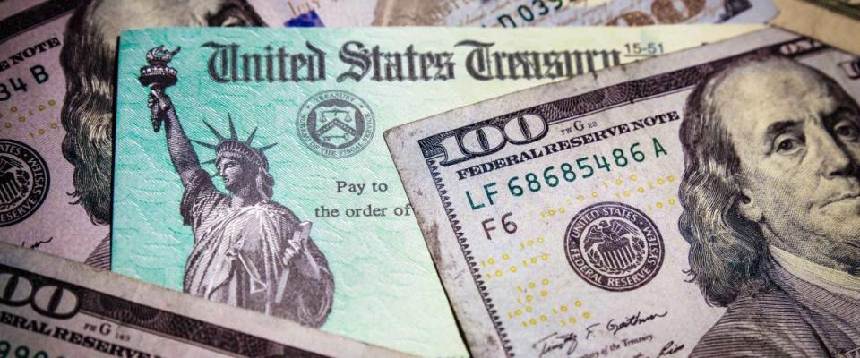 WASHINGTON DC - APRIL 2, 2020: United States Treasury check with US currency. Illustrates coronavirus stimulus payment