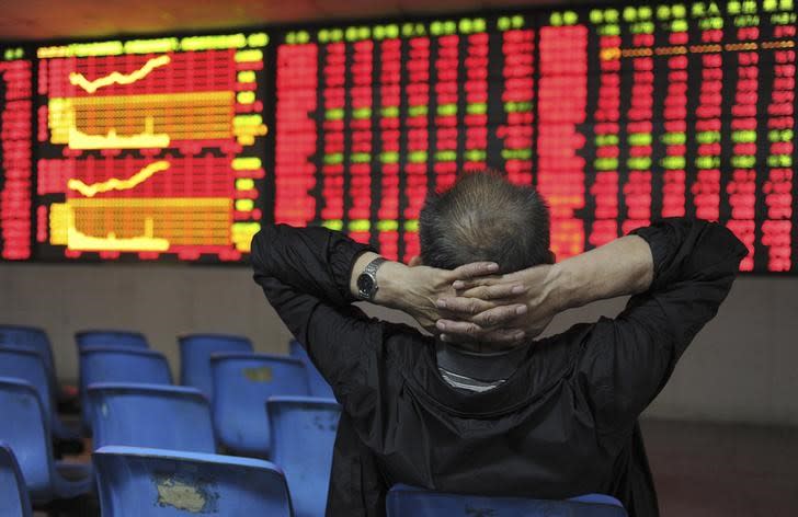 An investor places his hands on the back of his head in front of an electronic board showing stock information at a brokerage house in Hefei, Anhui province May 2, 2012. REUTERS/Stringer/Files