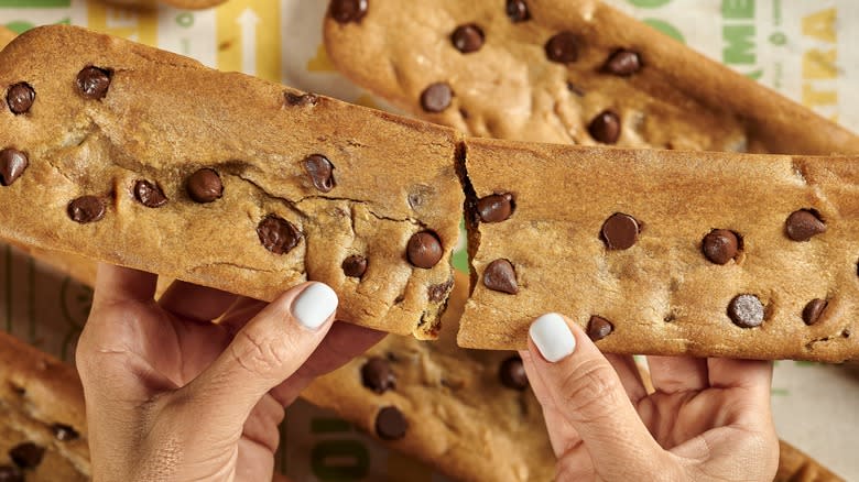 splitting a Subway footlong chocolate chip cookie in half