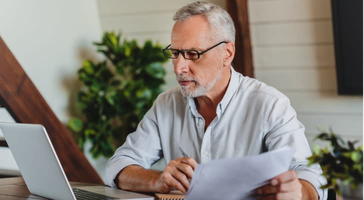 A man nearing retirement looks at his finances to estimate how much his taxes will be.