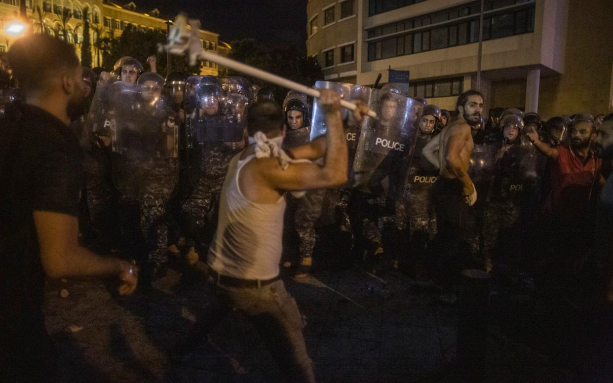 A protester attacks riot police outside the main government offices, the Grand Serail, in Beirut, - Sam Tarling