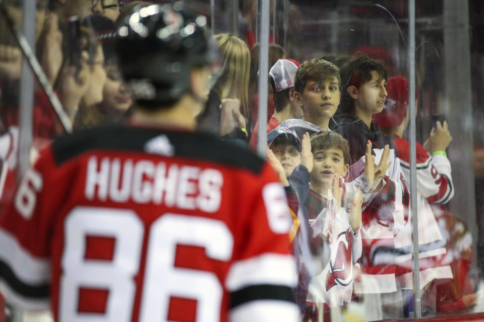 New Jersey Devils fans watch center Jack Hughes (86) warm up before the start of an NHL hockey game against the Florida Panthers, Monday, Oct. 14, 2019, in Newark, N.J. (AP Photo/Mary Altaffer)