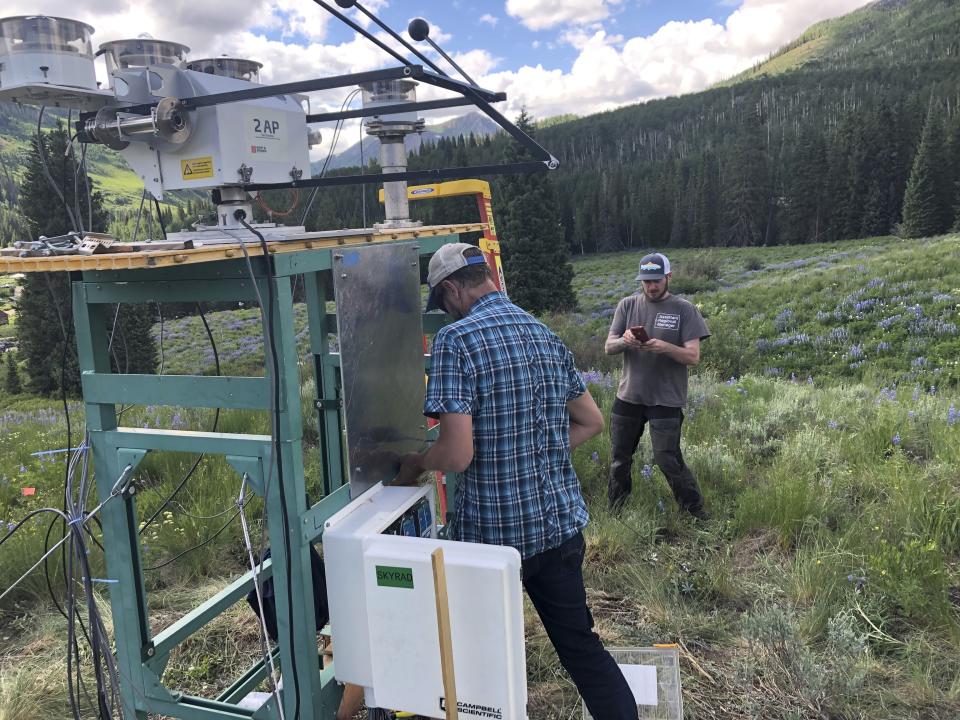 In this July 1, 2021, provided by Lawrence Berkeley National Laboratory, Heath Powers, center, site manager for the second Atmospheric Radiation Measurement mobile facility, helps set up radiometers for ARM's Surface Atmosphere Integrated Field Laboratory (SAIL) field campaign in Gothic, Colo. Federal scientists are launching an effort to better understand the hydrology in the U.S. West. The U.S. Department of Energy on Tuesday, Aug. 24 announced a new kind of climate observatory near the headwaters of the Colorado River. (David Chu/Lawrence Berkeley National Laboratory via AP)