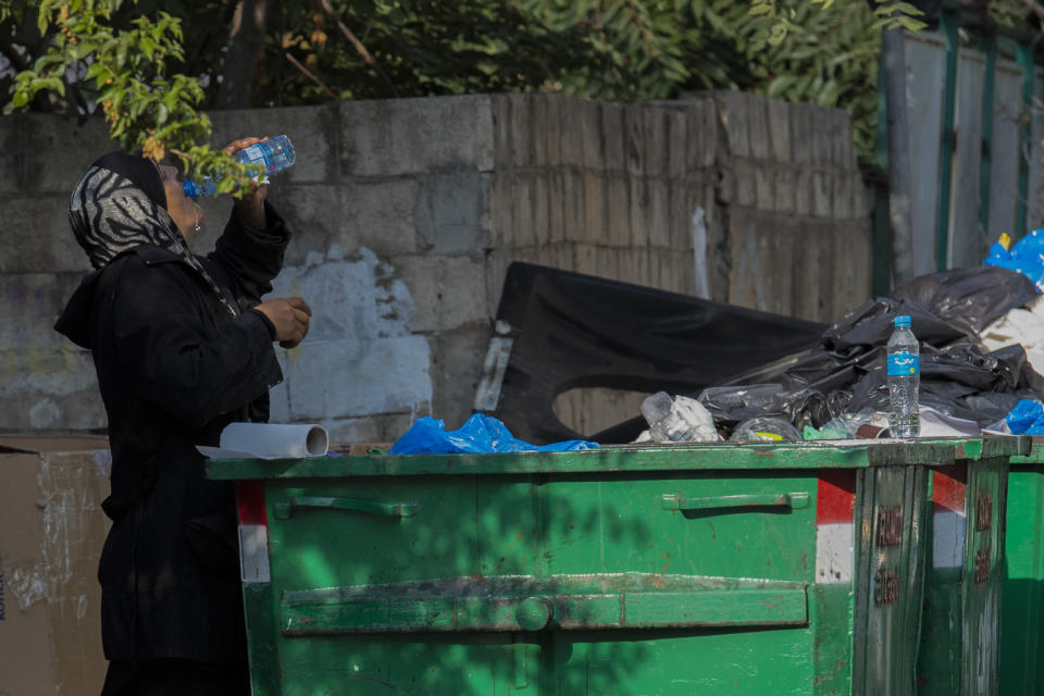 A homeless woman drinks water from a garbage dumpster in Beirut, Lebanon, Thursday, July 23, 2020. Lebanon should quickly form a reform-minded government to carry out badly needed reforms to help get the tiny country out of its severe economic crisis where the Real GDP growth is projected to contract nearly 20% in 2020 and a crash in local currency led to triple-digit inflation rates, the World Bank said Tuesday. (AP Photo/Hassan Ammar)