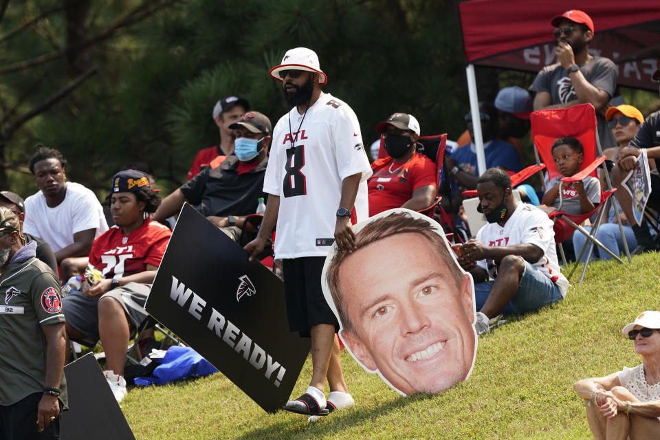 A man carries a cardboard cutout of Atlanta Falcons quarterback Matt Ryan (2) as he and about 1,000 people watch during Falcons NFL training camp football practice Saturday, July 31, 2021, in Flowery Branch, Ga. (AP Photo/John Bazemore)