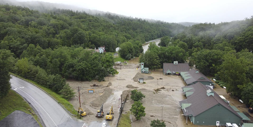 In this Tuesday, July 11, 2023 image provided by Pat Moore, construction vehicles stand by as muck, mud and floodwater block a section of Route 203 in Ludlow, Vt. (Pat Moore via AP)