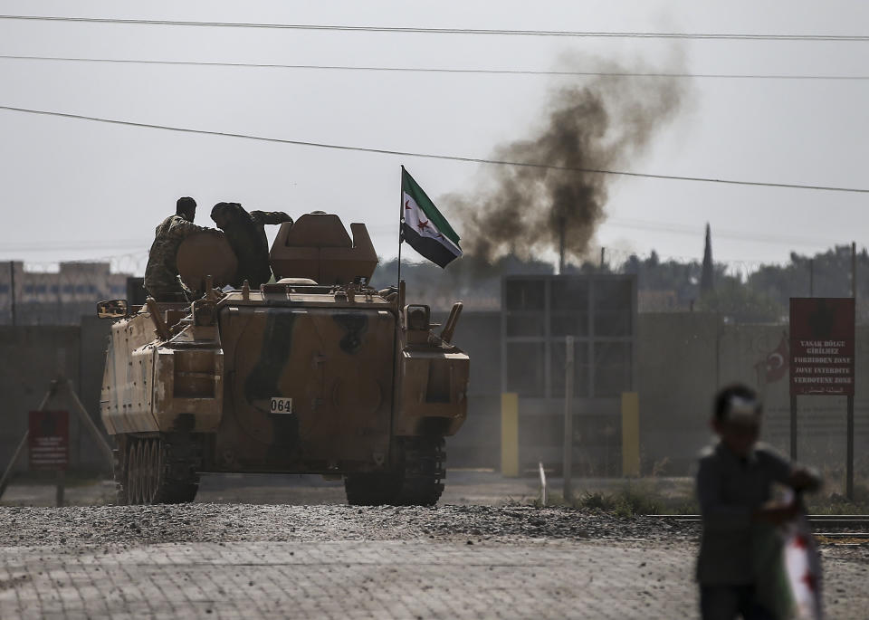 Turkish-backed Syrian opposition fighters on an armoured personnel carrier drive to cross the border into Syria, in Akcakale, Sanliurfa province, southeastern Turkey, Friday, Oct. 18, 2019. Fighting continued in a northeast Syrian border town at the center of the fight between Turkey and Kurdish forces early Friday, despite a U.S.-brokered cease-fire that went into effect overnight. (AP Photo/Emrah Gurel)