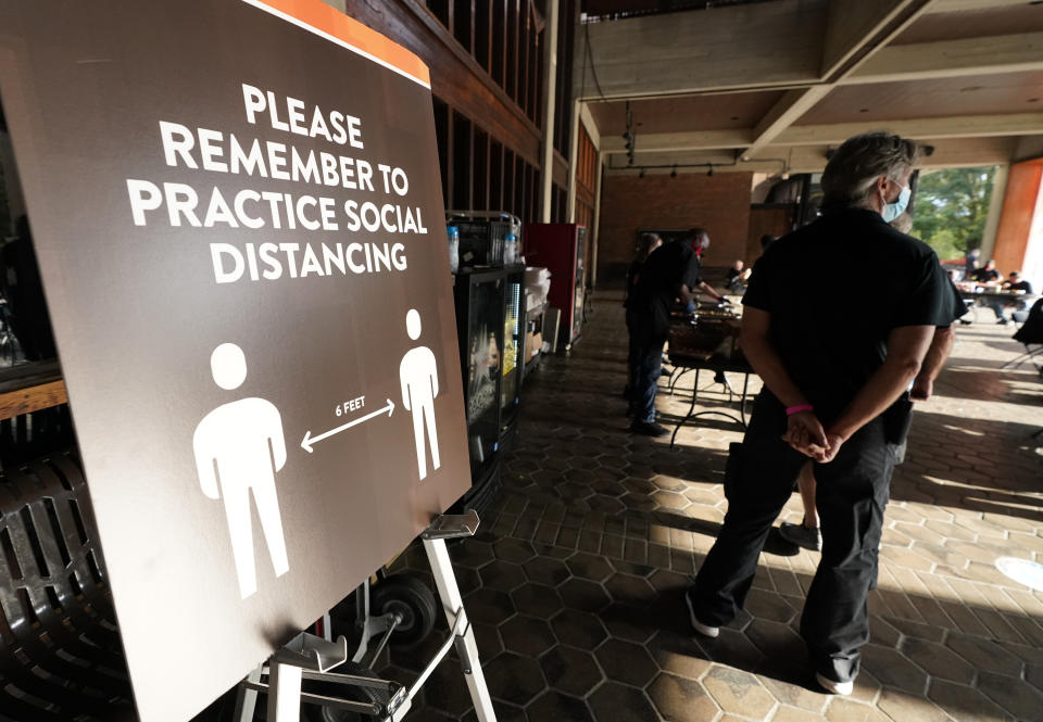 Event staff stand at the entrance to the Grand Ole Opry House stand near signs encouraging social distancing during the 55th annual Academy of Country Music Awards on Wednesday, Sept. 16, 2020, in Nashville, Tenn. (AP Photo/Mark Humphrey)