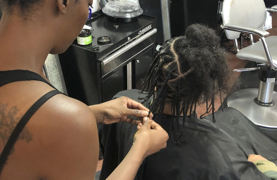 FILE - Shana Bonner, left, styles the hair of Pho Gibson at Exquisite U hair salon on, July 3, 2019, in Sacramento, Calif. People of color in the industry trace bias and discrimination in predominantly white salons to the sidelining of formal education focused on Black hair. Horror stories are not uncommon, from outright refusal of service to botched treatments and cuts by stylists who don't know what they're doing. (AP Photo/Kathleen Ronayne, File)