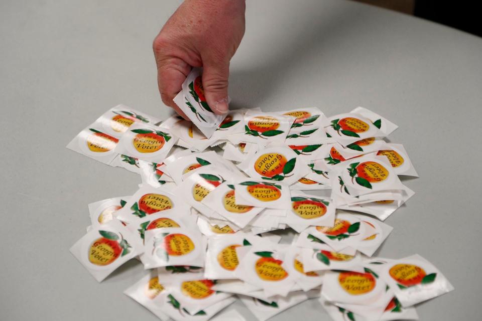 A voter picks up a peach "Georgia Voter" sticker after casting his ballot on Tuesday May 24, 2022 in Savannah, Georgia.