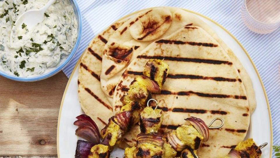 marinated chicken and onion kebabs arranged on a white oval plate with grilled pita bread