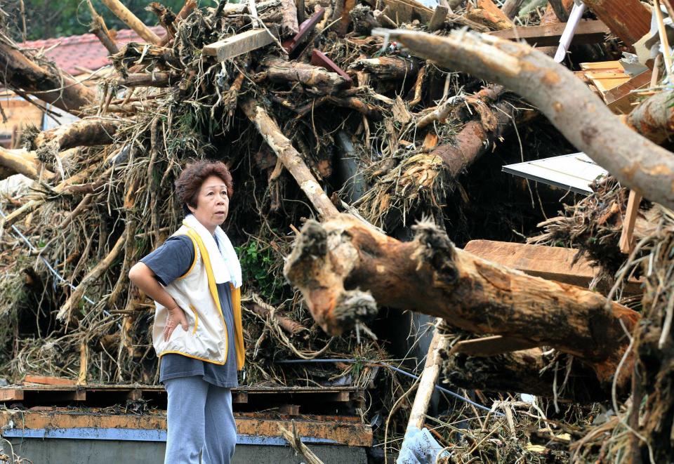 A woman reacts in front of collapsed houses following a landslide caused by Typhoon Wipha on Izu Oshima island, south of Tokyo, in this photo taken by Kyodo October 16, 2013. Eight people were killed and over 30 missing, with nearly 20,000 people ordered to evacuate and hundreds of flights cancelled as Typhoon Wipha pummelled the Tokyo region on Wednesday, leaving piles of wreckage on one small island but largely sparing the capital. (REUTERS/Kyodo)