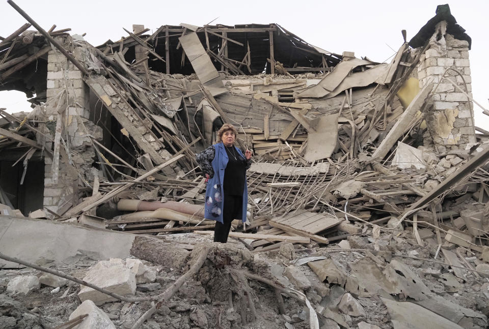 Home owner, Lida Sarksyan, stands near her house destroyed by shelling from Azerbaijan's artillery during a military conflict in Stepanakert, the separatist region of Nagorno-Karabakh, Saturday, Oct. 17, 2020. The latest outburst of fighting between Azerbaijani and Armenian forces began Sept. 27 and marked the biggest escalation of the decades-old conflict over Nagorno-Karabakh. The region lies in Azerbaijan but has been under control of ethnic Armenian forces backed by Armenia since the end of a separatist war in 1994. (AP Photo)