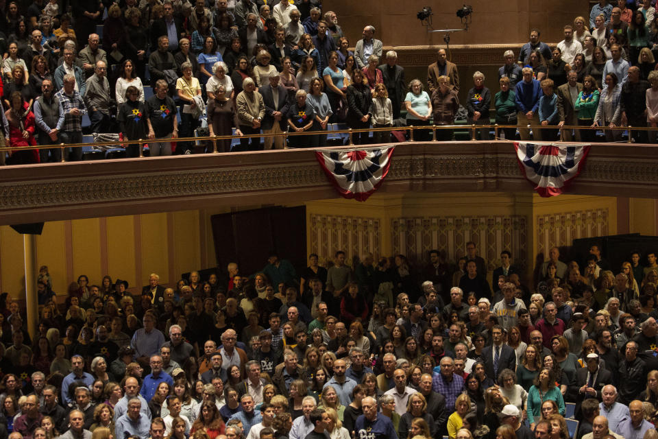 The crowd stands as the colors are presented to open the one-year commemoration of the Tree of Life synagogue attack at Soldiers & Sailors Memorial Hall and Museum, Sunday, Oct. 27, 2019, in Pittsburgh. A year ago, a gunman entered the Tree of Life synagogue and killed 11 members of three congregations, Dor Hadash, New Light and Tree of Life/Or L'Simcha, holding Shabbat services in the building. (AP Photo/Rebecca Droke)