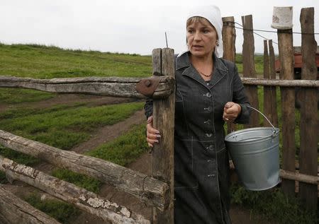 Zoya Lipnyagova carries a bucket at her house farm in the village of Kluchi, in Krasnoyarsk region, Siberia, in this file photo taken August 19, 2014. REUTERS/Ilya Naymushin/Files