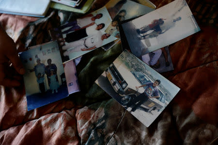 Lucia, wife of Ronald Blanco, 37, who was shot dead outside his house, displays photos of Blanco at her new home after fleeing from her neighbourhood, in Tegucigalpa, Honduras, November 13, 2018. On the day of Blanco's funeral Lucia fled from the cemetery with her children, never to return home. REUTERS/Edgard Garrido