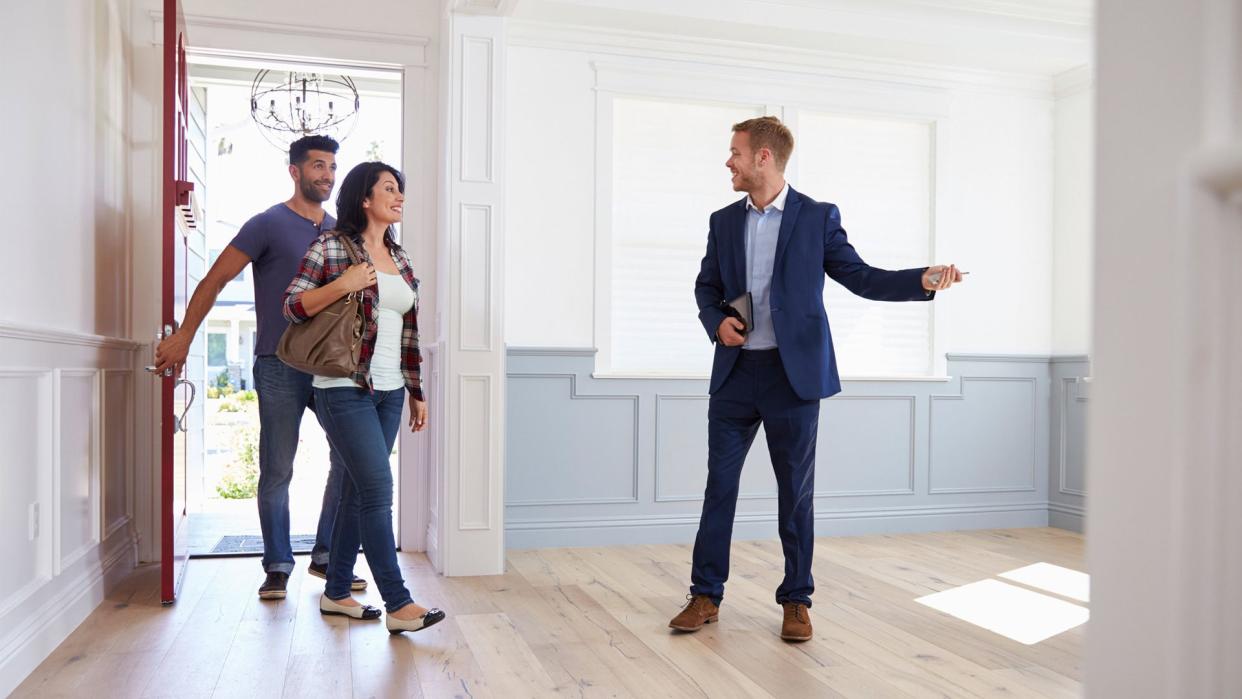 Realtor Showing Hispanic Couple Around New Home.