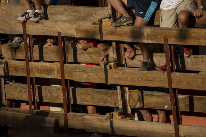Revelers stand on wooden barriers to watch a bull festival in the village of Atanzon, central Spain, Monday, Aug. 29, 2022. The deaths of eight people and the injury of hundreds more after being gored by bulls or calves have put Spain’s immensely popular town summer festivals under scrutiny by politicians and animal rights groups. There were no fatalities or injuries in Atanzon. (AP Photo/Bernat Armangue)