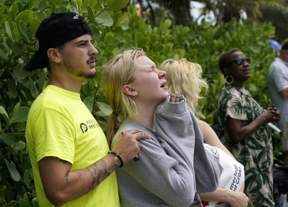 ADDS NAME OF HEVIA'S MOTHER AND THAT SHE DIED IN THE COLLAPSE - Ariana Hevia, of New Orleans, center, stands with Sean Wilt, left, on Friday, June 25, 2021, near the 12-story beachfront condo building that collapsed on Thursday in Surfside, Fla., north of Miami. Hevia's mother, Cassondra Billedeau-Stratton, lived in the building and is listed among those who died in the collapse. (AP Photo/Lynne Sladky)