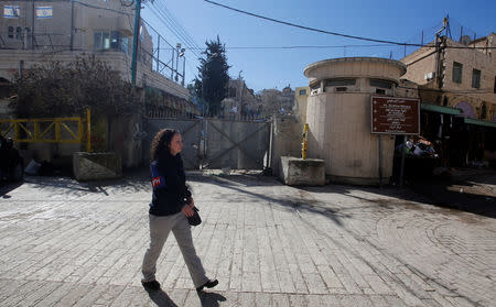 A member of the Temporary International Presence in Hebron (TIPH) walks past the Beit Romano settlement in Hebron, in the Israeli-occupied West Bank January 29, 2019. REUTERS/Mussa Qawasma