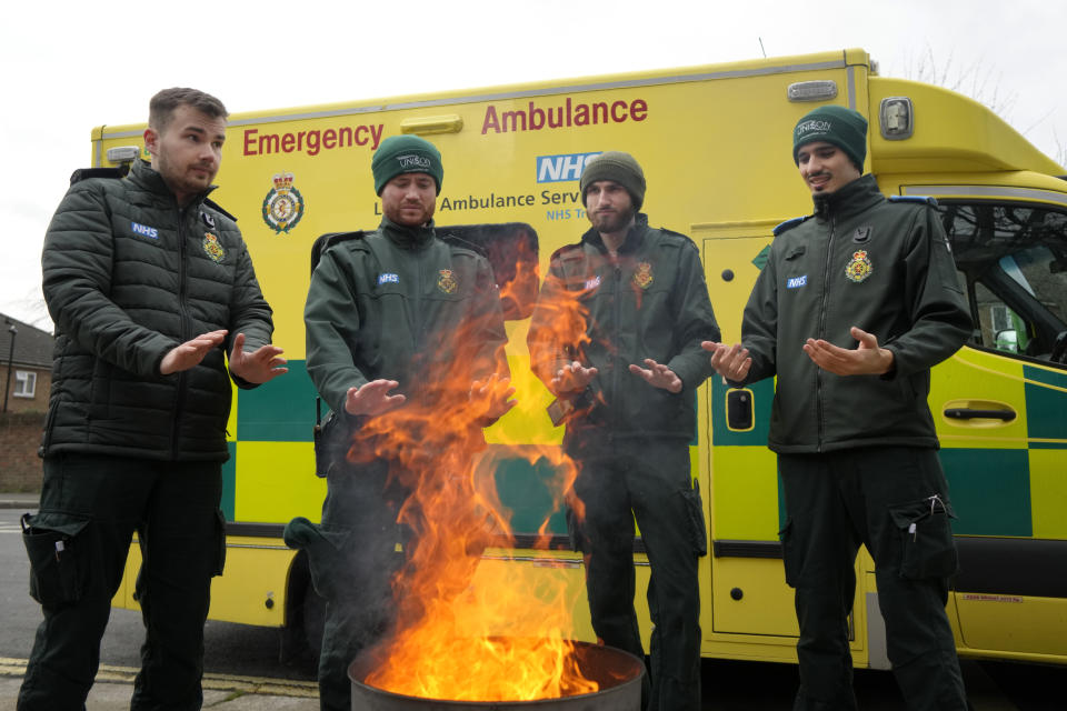 Ambulance workers keep warm around a brazier as they stand on a picket line in London, Wednesday, Jan. 11, 2023. Around 25,000 U.K. ambulance workers have gone on strike as they walked out for the second time since December in an ongoing dispute with the government over pay. The industrial action by paramedics, drivers and call handlers was the latest in a wave of strikes in recent months.(AP Photo/Kirsty Wigglesworth)