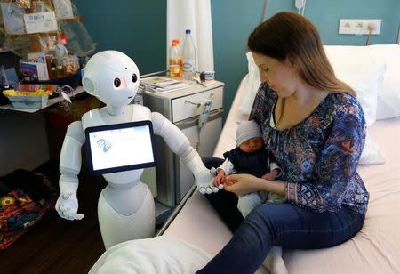 New recruit "Pepper" the robot, a humanoid robot designed to welcome and take care of visitors and patients, holds the hand of a new born baby next to his mother at AZ Damiaan hospital in Ostend, Belgium June 16, 2016. REUTERS/Francois Lenoir