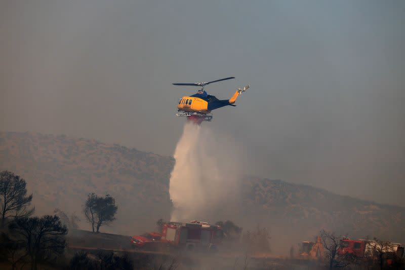 Un helicóptero de extinción de incendios arroja agua mientras arde un incendio forestal en Keratea, cerca de Atenas, Grecia