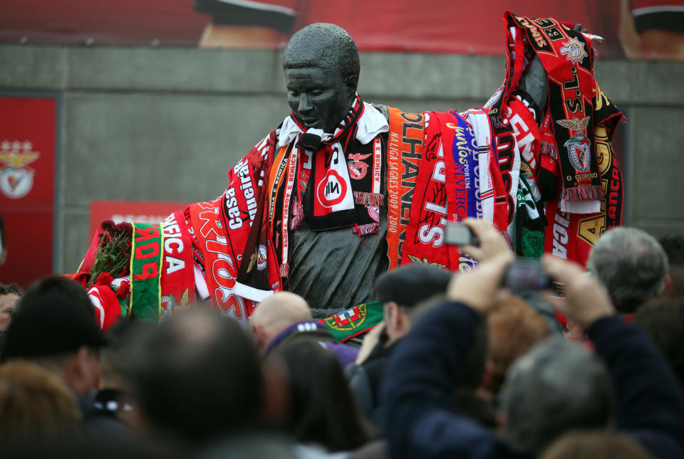 People gather around the sculpture of the Portuguese soccer player legend Eusebio covered by scarfs, at the Benfica's Luz stadium in Lisbon, Sunday, Jan. 5, 2014. Eusebio, the Portuguese football star who was born into poverty in Africa but became an international sporting icon and was voted one of the 10 best players of all time, has died aged 71, his longtime club Benfica said. (AP Photo/Francisco Seco)