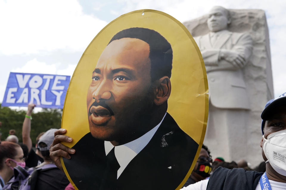 FILE - A man holds a portrait of the Rev. Martin Luther King, Jr., at the Martin Luther King Jr. Memorial during the March on Washington, Friday Aug. 28, 2020, in Washington. (AP Photo/Carolyn Kaster, File)