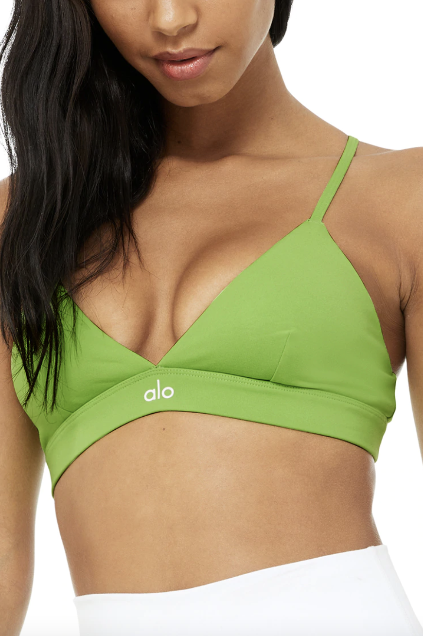 model wearing white bottoms and Alo Splendor Bra in Green Apple (Photo via Alo Yoga)